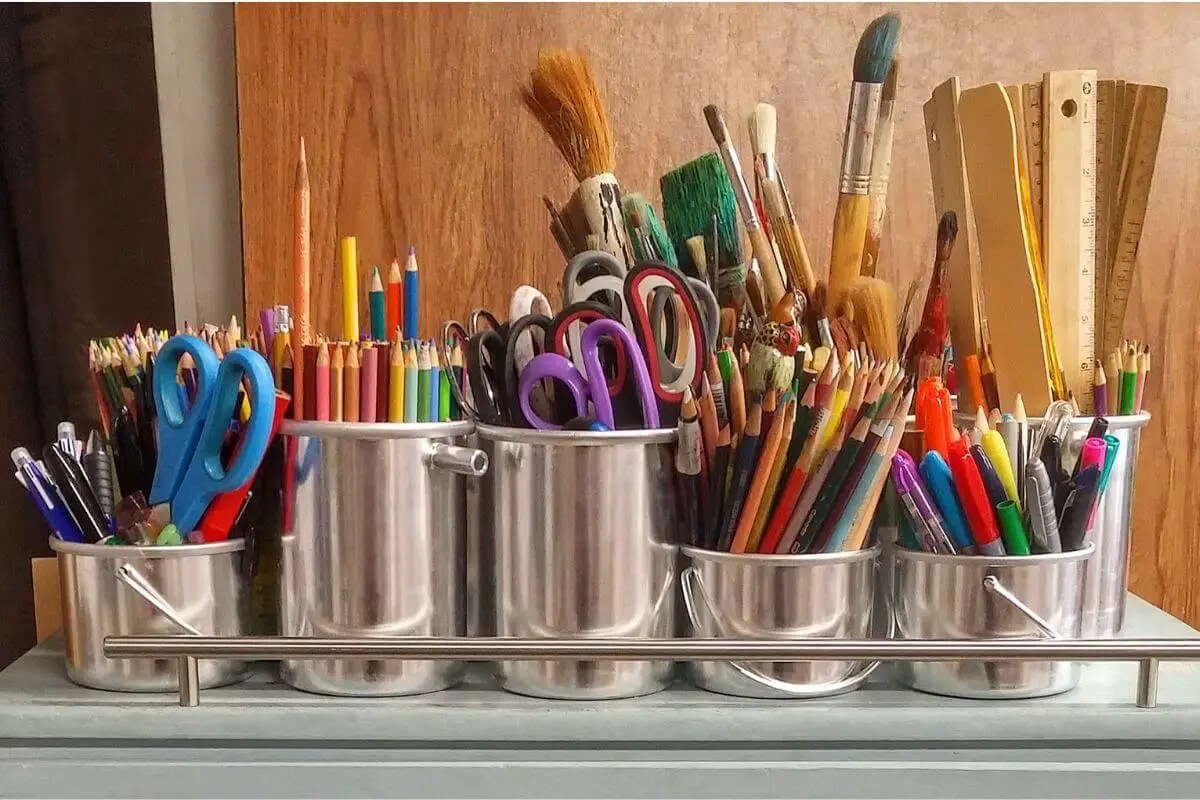 Silver pots full of paint brushes and pens