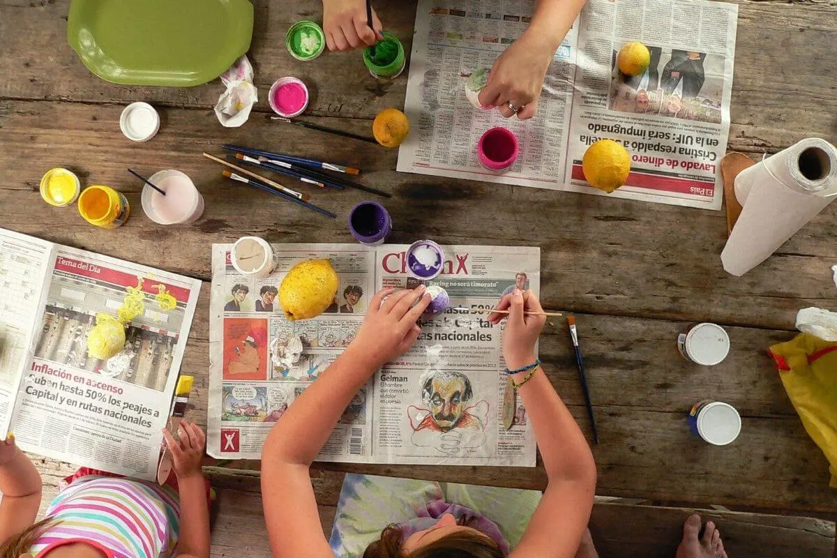 Children doing craft on a newspaper outside