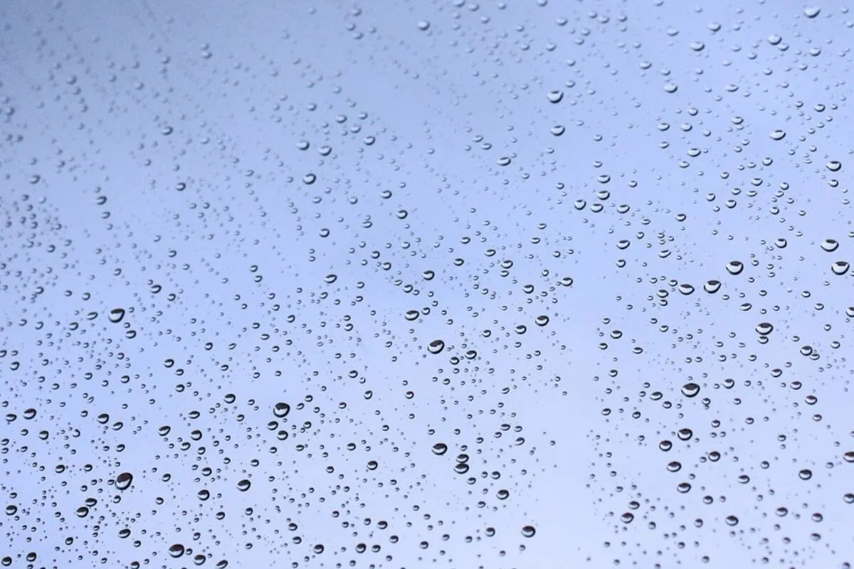 Light blue sky with rain drops on a window